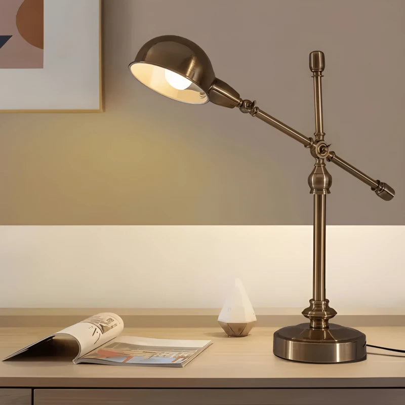 Lampe de bureau vintage cuivrée arrondie allumée sur un bureau en bois clair