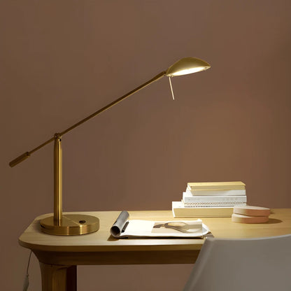 Lampe dorée articulée sur un bureau en bois