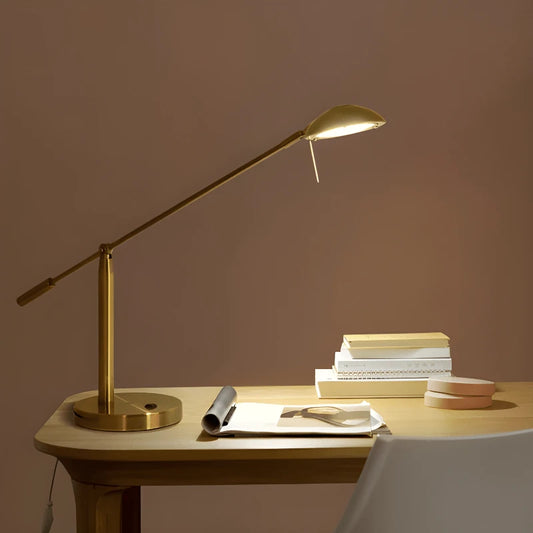 Lampe dorée articulée sur un bureau en bois