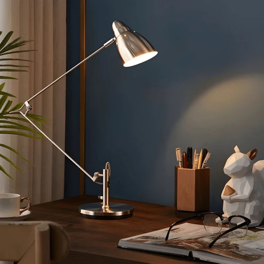 Lampe de bureau articulée chromée qui éclaire un bureau en bois foncé