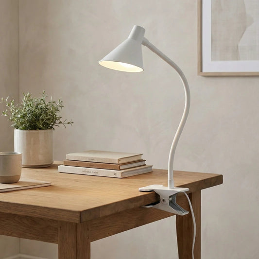 Lampe de Bureau LED à Pince Lumia blanche placée sur le côté d'un espace de travail en bois