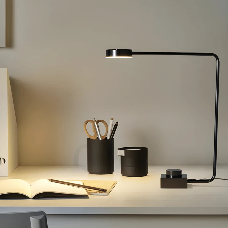 Lampe de Bureau LED Minimaliste Art qui éclaire un cahier sur un bureau blanc