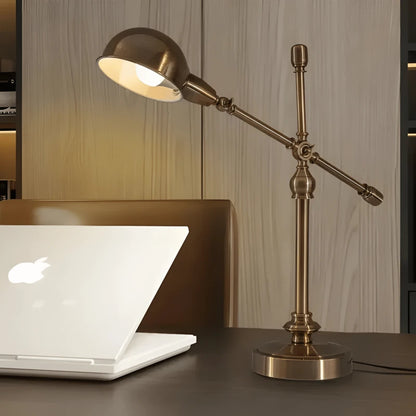 Lampe de bureau vintage cuivrée arrondie au-dessus d'un espace de travail en bois