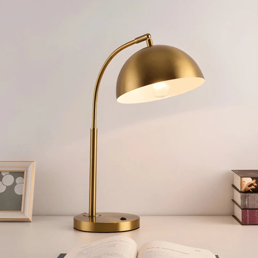 Lampe de bureau vintage dorée placée au centre d'un bureau de lecture