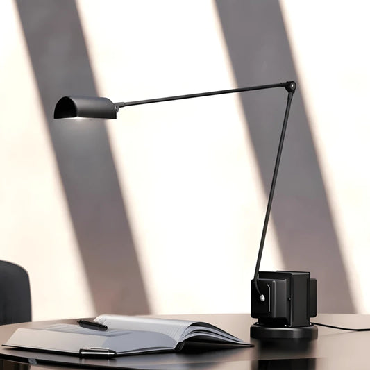 Lampe de Bureau Articulée Verona qui éclaire un livre sur un espace de travail noir