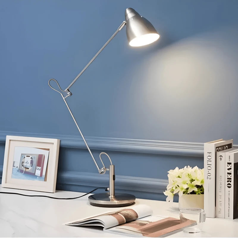 Lampe de bureau articulée chromée sur un bureau blanc et arrière plan mur bleu