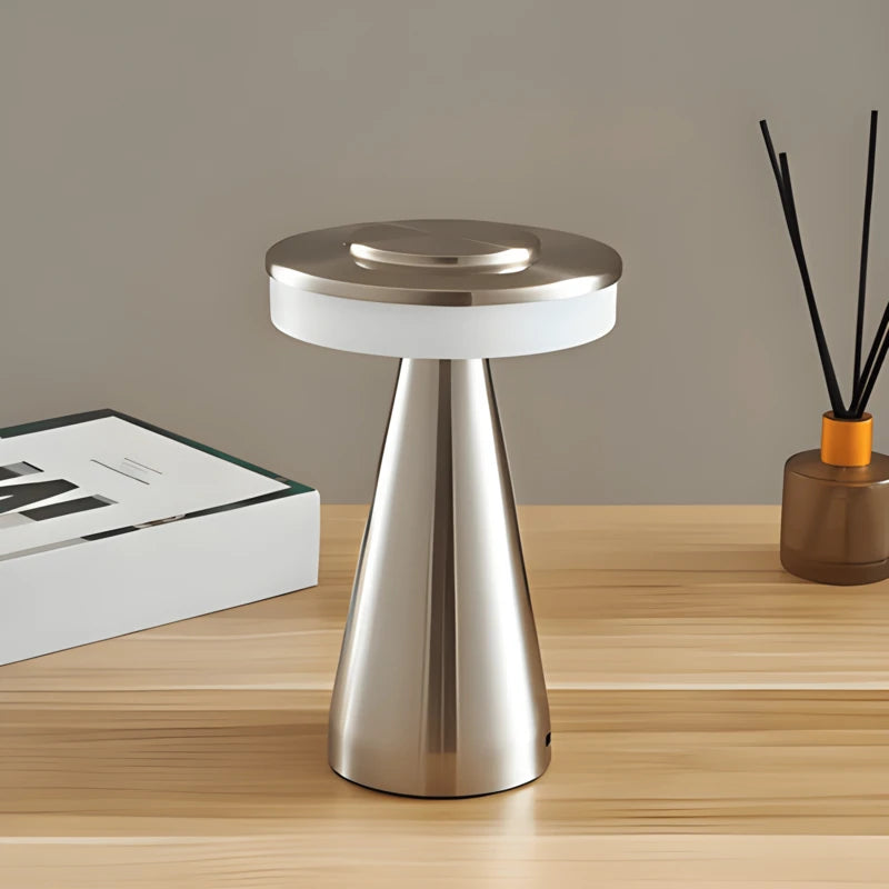 Lampe de bureau champignon LED en argent placée un bureau en bois clair