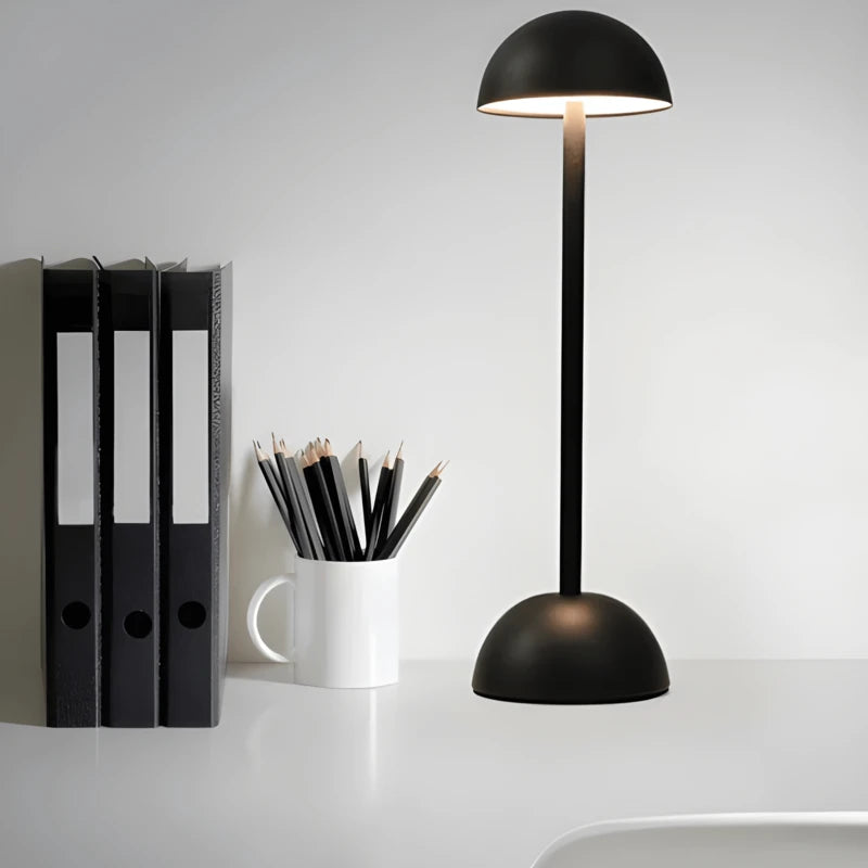Lampe de bureau champignon moderne tactile noire allumée au-dessus d'un espace de travail blanc