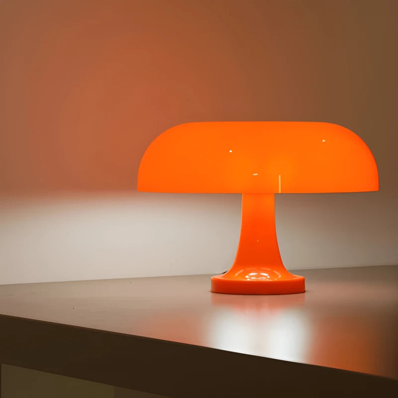 Une lampe de bureau champignon orange posée sur un bureau en bois