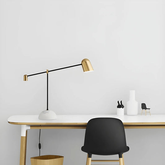 Lampe de bureau LED design articulée dorée sur un bureau blanc et en bois