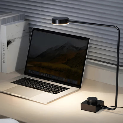 Lampe de Bureau LED Minimaliste Art éclairante un ordinateur portable placé sur un bureau blanc