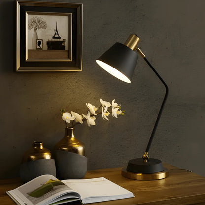 Lampe de bureau LED noir et dorée sur un bureau moderne en bois foncé