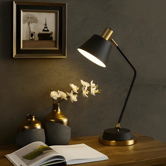 Lampe de bureau LED noir et dorée sur un bureau moderne en bois foncé