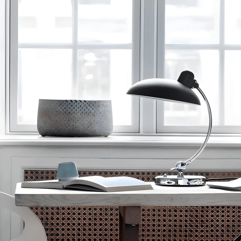 Lampe de bureau style années 50 noire située sur un bureau en bois blanc