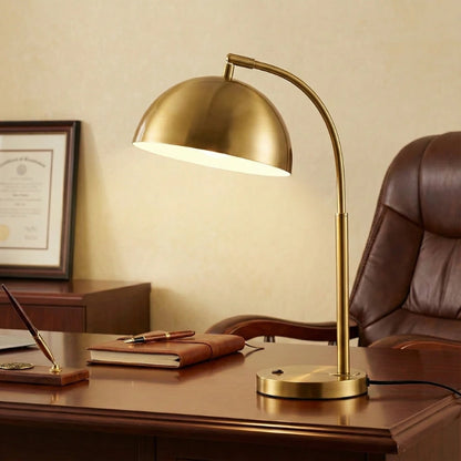 Lampe de bureau vintage dorée au-dessus d'un bureau en bois foncé 