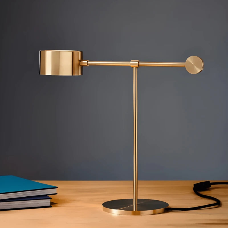 Lampe dorée design T sur un bureau en bois